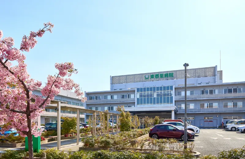 花が彩る駐車場の奥に、病院の建物が佇む